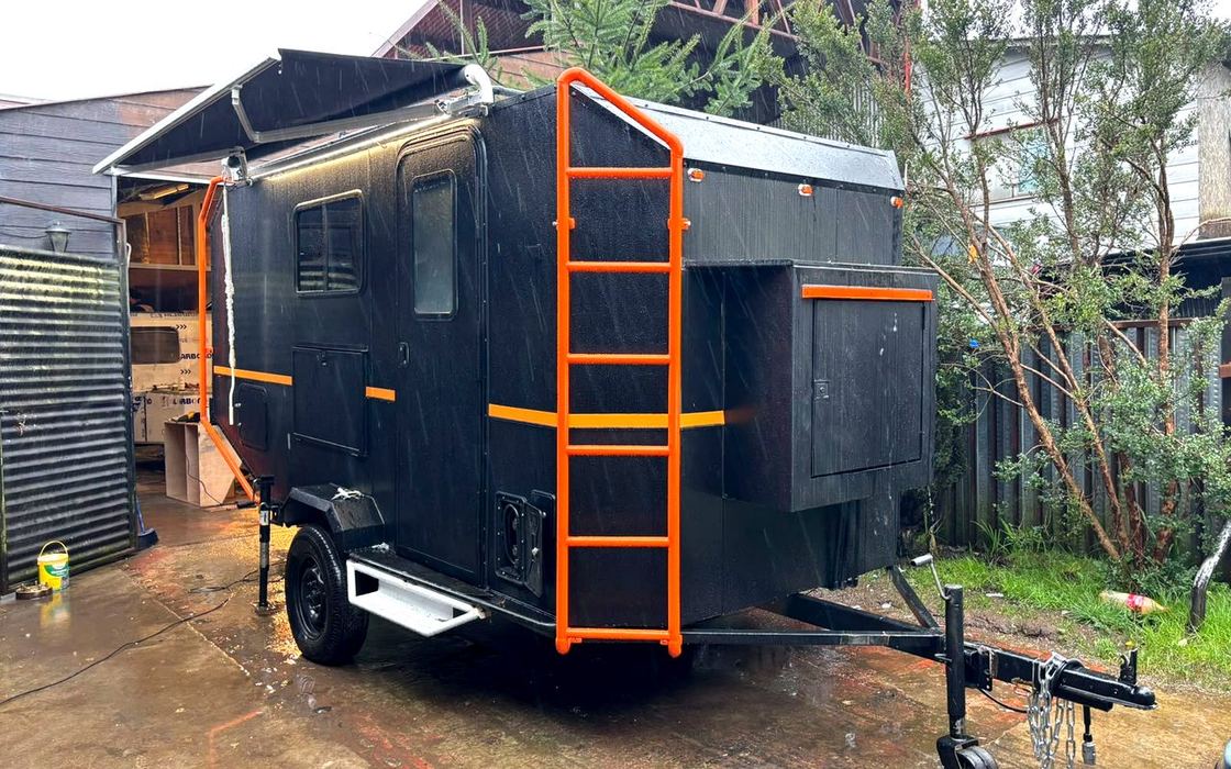 Camper para 4 personas de Patagonia Camper Chile, exterior negro con detalles naranjos y toldo desplegado